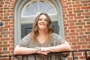 woman in black and white leopard print shirt standing near brown brick wall